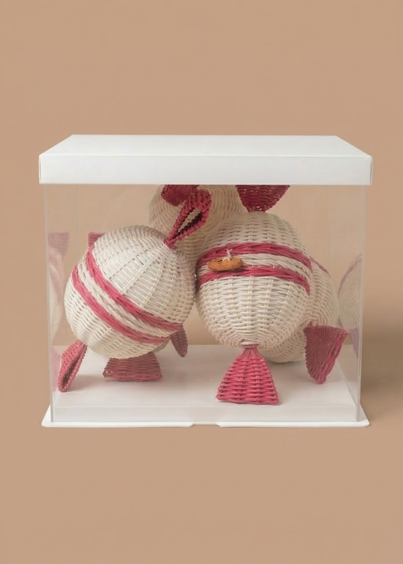 Rattan candy parcels in a see through box with a white lid on a beige background