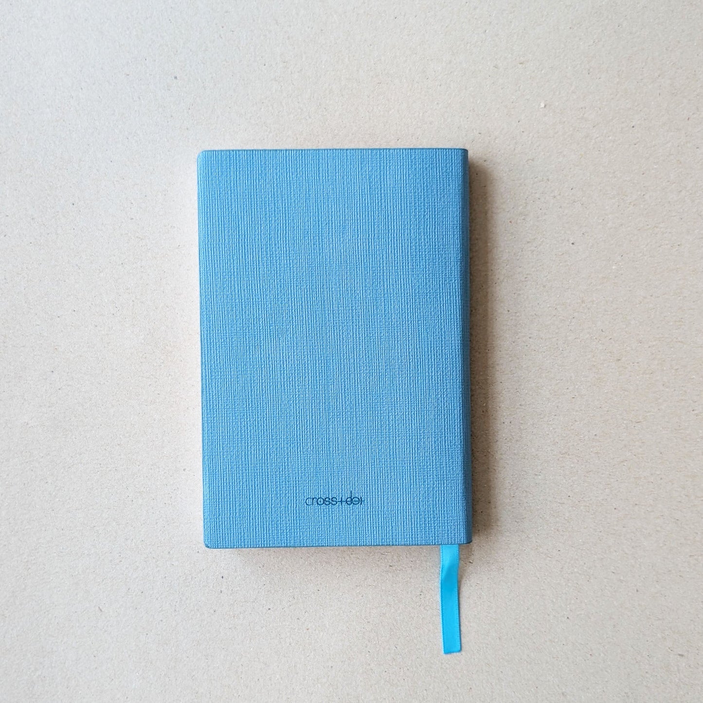 Blue notebook with a visible brand name on a light gray background