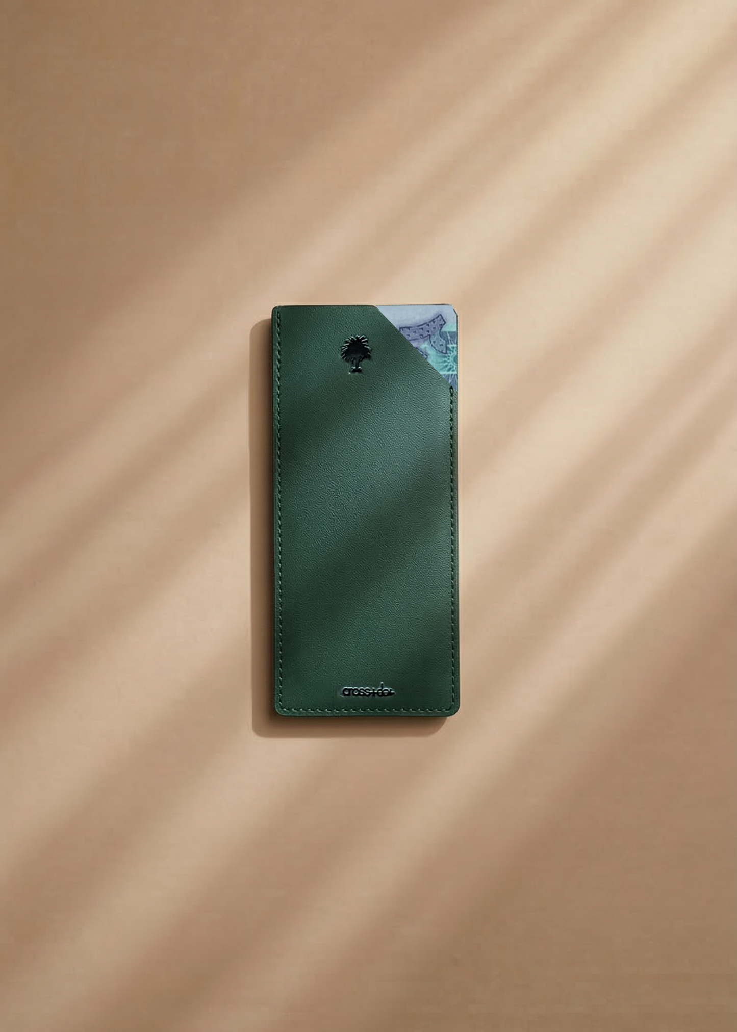 Green leather money envelope with a palm tree debossed on a beige surface