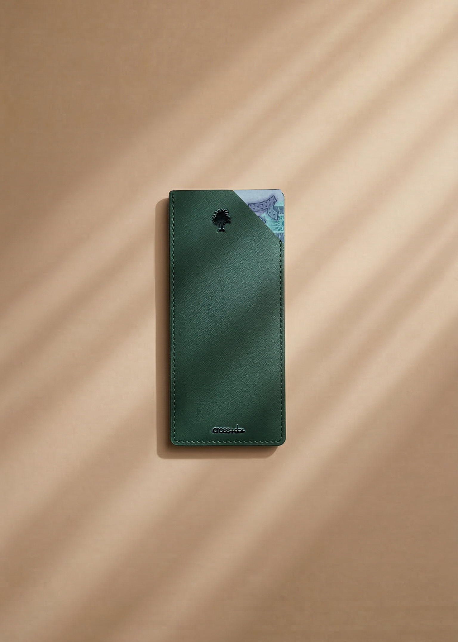 Green leather money envelope with a palm tree debossed on a beige surface