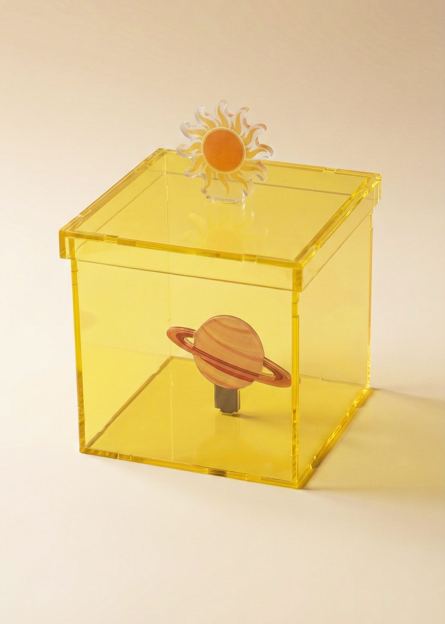 Yellow transparent box with solar system-themed objects on a beige background